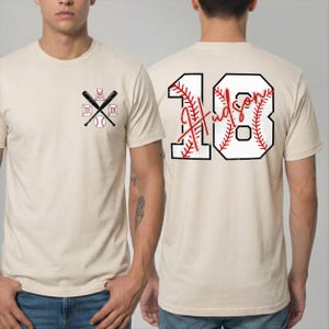 Rear view of the custom baseball shirt showing the large back print. The number "18" is printed in a large, block font with red baseball stitching details inside the numbers. The name "Hudson" is written in a red script font across the center of the number.