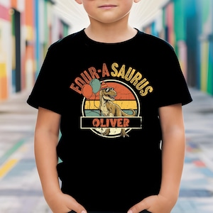 May include: Black t-shirt featuring a dinosaur graphic with the text "FOUR-A-SAURUS" and the name "OLIVER". The design includes a dinosaur wearing sunglasses and a party hat, with balloons in the background. The design is in a retro style.