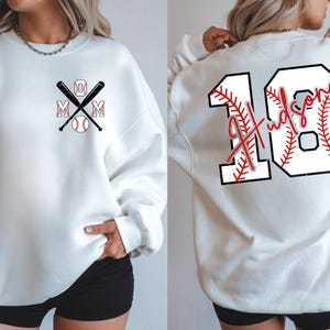 Detailed close-up of the back graphic. The white fill of the number "18" has a subtle distressed texture. The red stitching lines mimic the seams of a real baseball. The script name "Hudson" contrasts boldly against the number, making it easy to read from the bleachers.