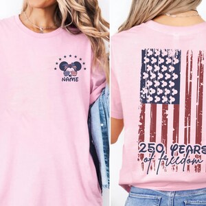 A woman wearing a pink t-shirt with an American flag design and the text "250 YEARS OF FREEDOM" printed on it.