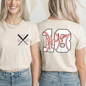A beige t-shirt featuring a "Pocket Style" baseball design on the front left chest. Two black baseball bats are crossed in an "X" shape. The letters "M" "O" "M" are placed around the bats, with a white baseball at the bottom. The design is simple and sporty.