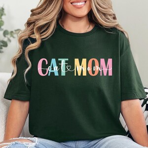 a woman sitting on a couch wearing a green t - shirt with the word cat