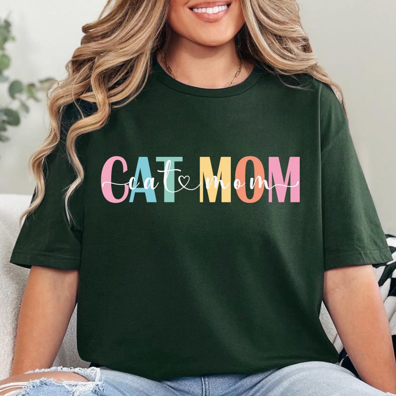 a woman sitting on a couch wearing a green t - shirt with the word cat