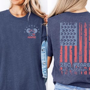 A woman wearing a blue t-shirt with a graphic design on the back, featuring an American flag and the text "250 YEARS OF FREEDOM".