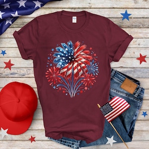a red t - shirt with a fireworks design on it