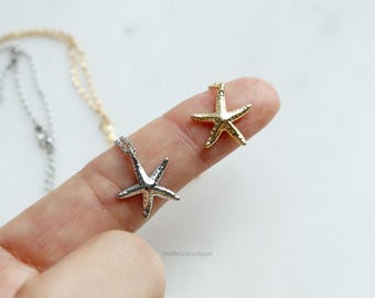 May include: Two delicate necklaces with a starfish pendant. One necklace has a gold starfish pendant and the other has a silver starfish pendant.