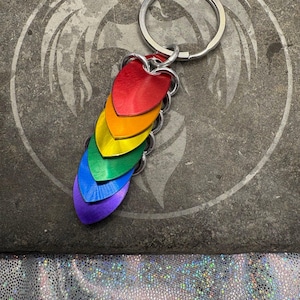 May include: Rainbow heart keychain with a silver key ring. The hearts are made of metal and are in the colors of the rainbow, from red to purple.