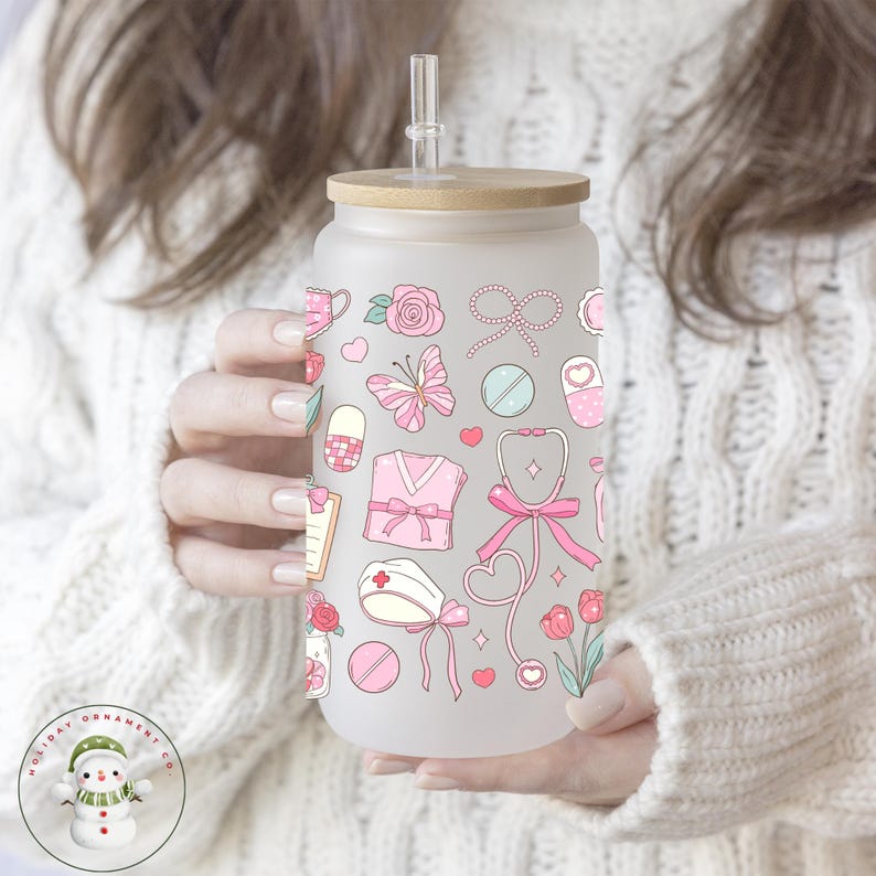 May include: Frosted glass tumbler with a bamboo lid and straw. The tumbler is decorated with pink medical-themed illustrations, including a stethoscope, pills, and a nurse's cap. The design is repeated around the entire glass.