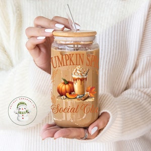 Puede incluir: Un vaso de vidrio transparente con tapa de bambú y una pajita. El vaso tiene un gráfico de un latte de especias de calabaza con el texto "Pumpkin Spice Social Club".