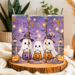 May include: A cylindrical metal tumbler with a straw, featuring a purple Halloween-themed design with three white ghosts wearing witch hats, holding orange jack-o'-lantern candy buckets, surrounded by stars, bats, and bunting flags.