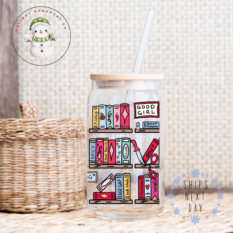 May include: A clear glass tumbler with a bamboo lid and a straw. The tumbler has a graphic of a bookshelf with colorful books and the text "GOOD GIRL" on a sign above the top shelf. The books have titles like "Filthy", "Spicy", "Forced Honesty", "Killer", "Smut", "Age Gap", "Safe Words", and "Fantasies".