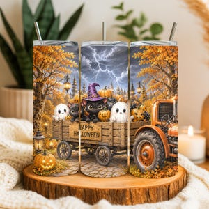 May include: A cylindrical metal tumbler with a straw featuring a Halloween scene of a black cat in a purple witch hat, white ghosts, and pumpkins in a wooden wagon labeled Happy Halloween, set against a backdrop of autumn trees and lightning.