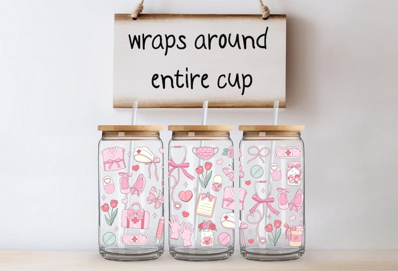 May include: Three glass tumblers with bamboo lids and straws, decorated with pink medical-themed illustrations. The tumblers feature a variety of medical symbols and the text "wraps around entire cup" on a wooden sign.
