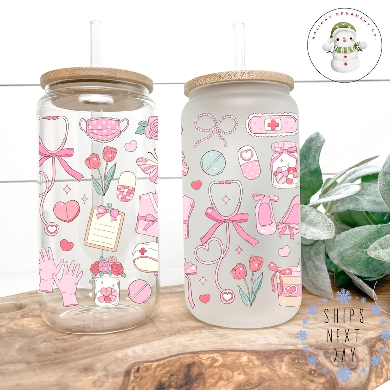 May include: Two glass tumblers with bamboo lids and straws. One is clear, the other frosted. Both feature pink medical-themed illustrations, including stethoscopes, hearts, and pills. The clear tumbler has a pink bow, and the frosted one has a pink ribbon. The text "SHIPS NEXT DAY" is visible.