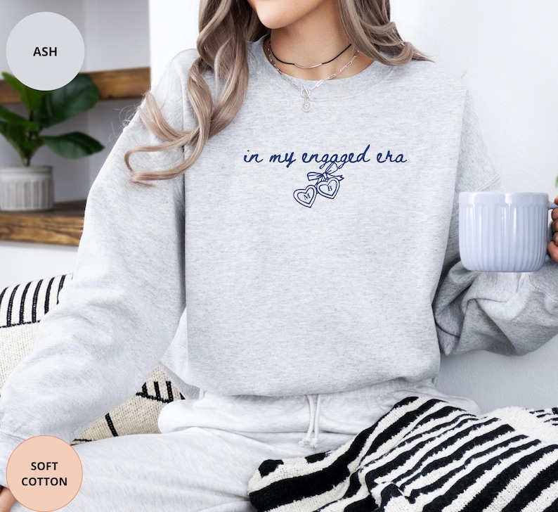 Ash Sweatshirt with custom black  text "in my engaged era" and heart lock graphic, perfect for brides-to-be and engagement gifts.