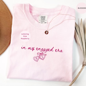 Blossom Comfort Colors® t-shirt with custom raspberry text "in my engaged era" and heart lock graphic, perfect for brides-to-be and engagement gifts.