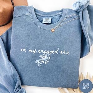 Blue Jean Comfort Colors® Sweatshirt with custom white text "in my engaged era" and heart lock graphic, perfect for brides-to-be and engagement gifts.