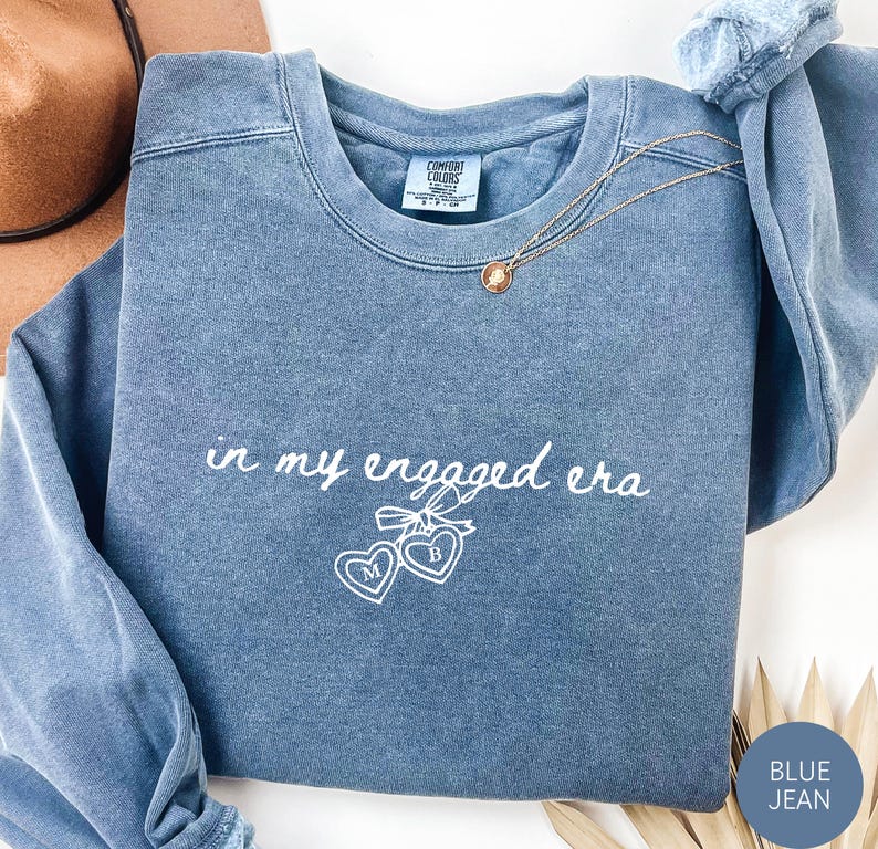 Blue Jean Comfort Colors® Sweatshirt with custom white text "in my engaged era" and heart lock graphic, perfect for brides-to-be and engagement gifts.