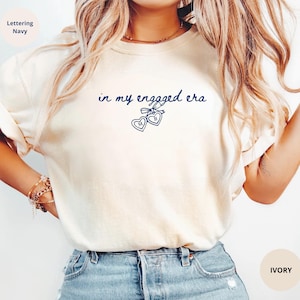 Ivory Comfort Colors® t-shirt with custom navy text " in my engaged era" and heart lock graphic, perfect for brides-to-be and engagement gifts.