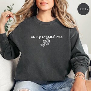 Pepper Comfort Colors® sweatshirt with custom white text "in my engaged era" and heart lock graphic, perfect for brides-to-be and engagement gifts.