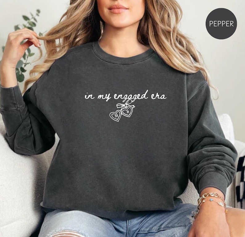 Pepper Comfort Colors® sweatshirt with custom white text "in my engaged era" and heart lock graphic, perfect for brides-to-be and engagement gifts.