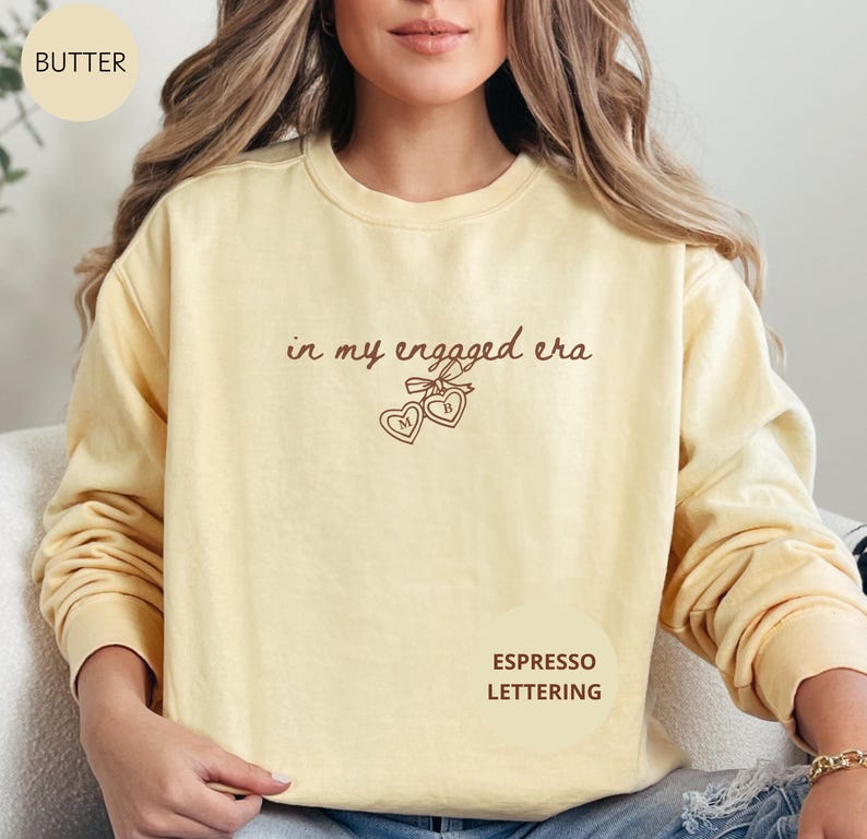Butter Comfort Colors® sweatshirt with custom espresso text "in my engaged era" and heart lock graphic, perfect for brides-to-be and engagement gifts.