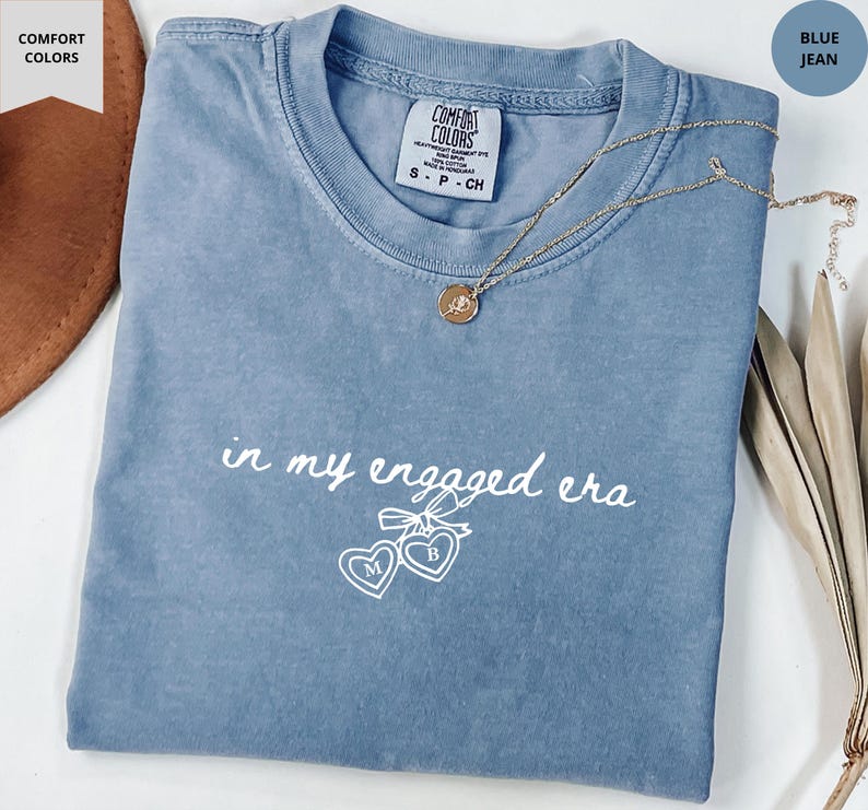 Blue Jean Comfort Colors® t-shirt with custom white text "in my engaged era" and heart lock graphic, perfect for brides-to-be and engagement gifts.