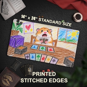 May include: A rectangular playmat measuring 35.56 cm by 60.96 cm with stitched edges. The surface features a colourful crayon-style drawing of a hamster sitting at a table playing a card game, with stacks of cards and various elemental symbols.