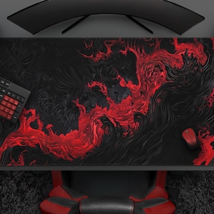 K&ouml;nnte beinhalten: Ein gro&szlig;es schwarzes und rotes Gaming-Mauspad mit einem wirbelnden, abstrakten Design. Eine schwarze Tastatur mit roten Tasten, eine rote Maus und ein roter Gamecontroller liegen auf dem Schreibtisch. Der Schreibtisch ist schwarz.
