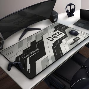 May include: A rectangular gaming mouse pad with a black, white, and gray geometric design. The text "D4T4" and "TECH/INTERFACE" are printed on the pad. A black mouse, controller, and other gaming accessories are on the desk.