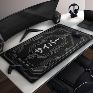 May include: Black rectangular gaming mouse mat featuring a circuit board design and Japanese text. A computer mouse, a game controller, and a curved monitor are on the white desk. Headphones sit on a stand.