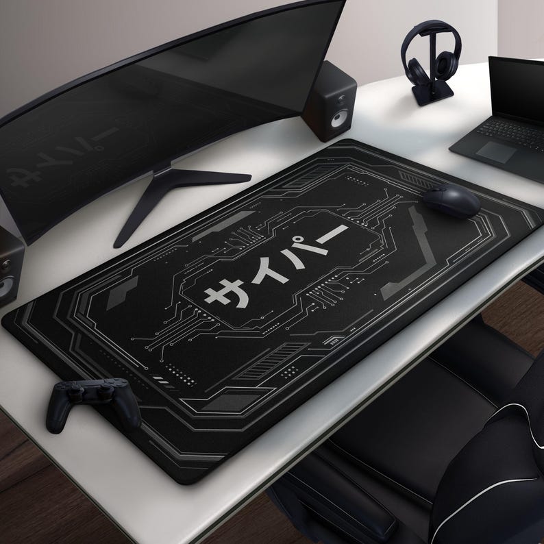 May include: Black rectangular gaming mouse mat featuring a circuit board design and Japanese text. A computer mouse, a game controller, and a curved monitor are on the white desk. Headphones sit on a stand.