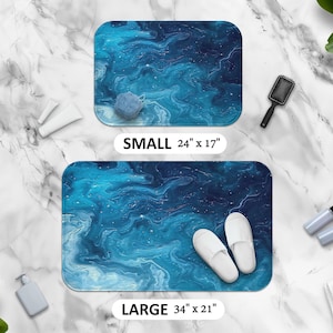 May include: Two bath mats with a blue abstract design. The smaller mat is 24 inches by 17 inches and the larger mat is 34 inches by 21 inches.