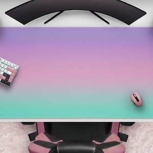 May include: A large desk mat with a gradient design, transitioning from purple to pink to teal. A white keyboard with pink accents, a pink mouse, and a pink game controller are on the mat. A curved monitor and speakers are above.