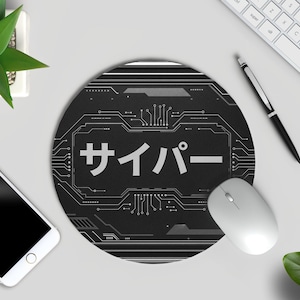 May include: A round black mouse mat featuring a circuit board design and Japanese text. The word "cyber" is written in white. A white mouse, keyboard, pen, and smartphone are also visible.