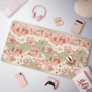 May include: A rectangular desk mat featuring a repeating pattern of cartoon pigs, strawberries, and small flowers on wavy bands of light pink and sage green. The pigs are depicted in various poses, including sleeping, standing, and holding strawberries.