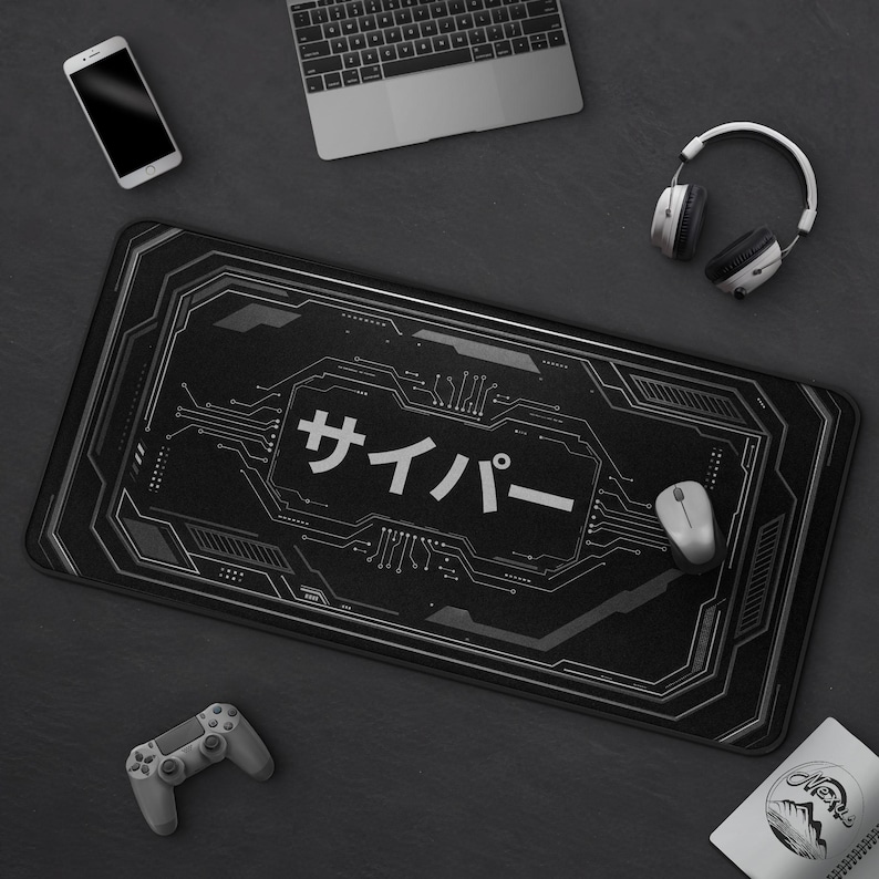 May include: Black rectangular gaming mouse mat with a circuit board design and Japanese text. A laptop, headphones, a mouse, a smartphone, and a game controller surround the mat.