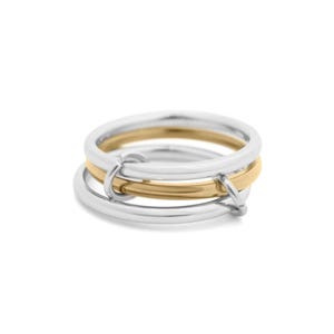 May include: A silver and gold ring with three interlocking bands. The ring features a gold band in the middle, with two silver bands on the top and bottom. The bands are connected with small silver connectors.