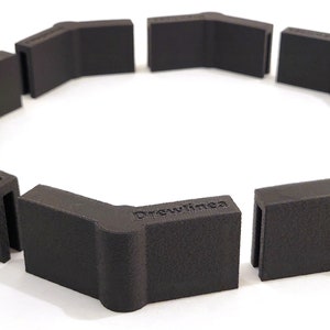 May include: A set of eight black plastic corner pieces, each with the word "Drewlinea" printed on the side. The pieces are arranged in a circle, forming a frame.