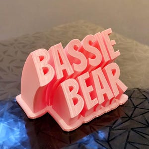 Op de afbeelding: Een roze 3D-geprint bord met de tekst "Bassie Bear".