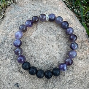 May include: A purple amethyst and black lava rock beaded bracelet with a silver spacer bead.