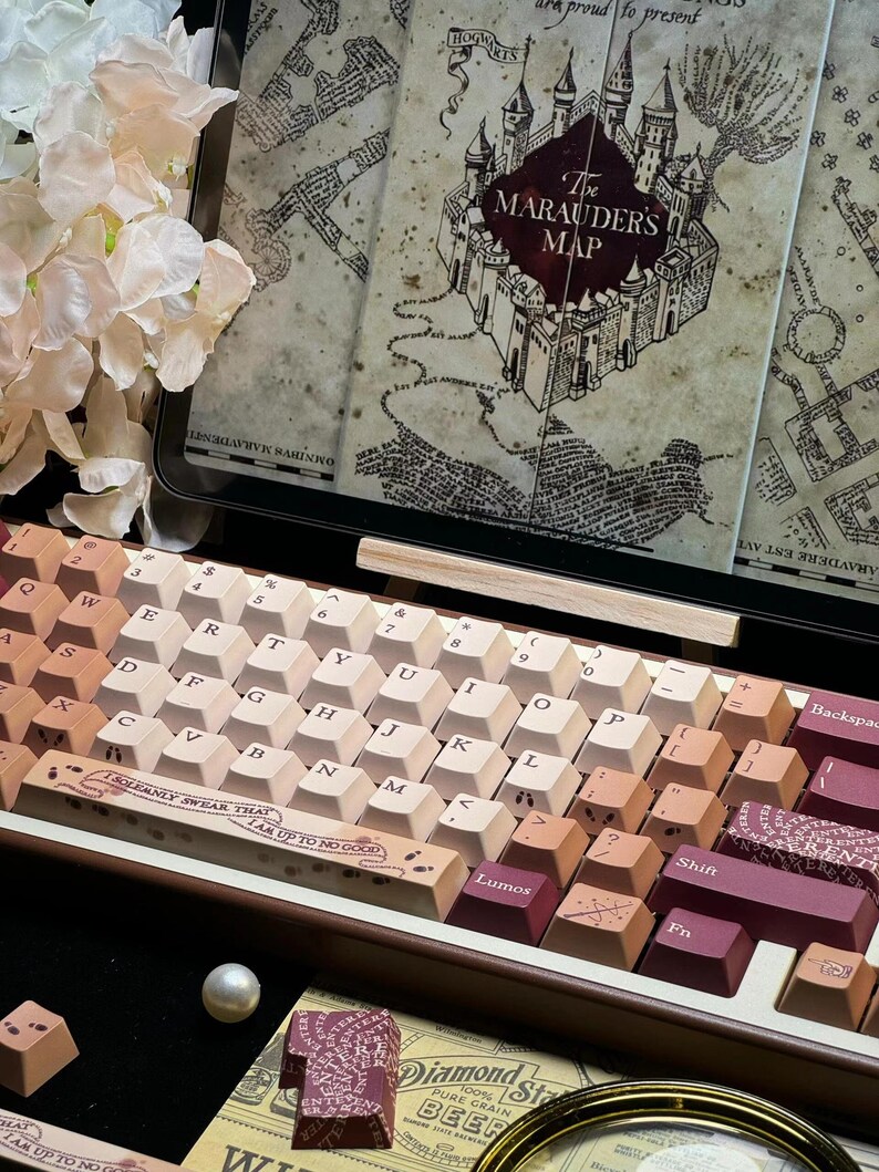 May include: A custom mechanical keyboard with gradient keycaps in shades of brown and cream. The keyboard features a design inspired by "The Marauder's Map" from the Harry Potter series. The keyboard has a wooden frame and a display of the map.