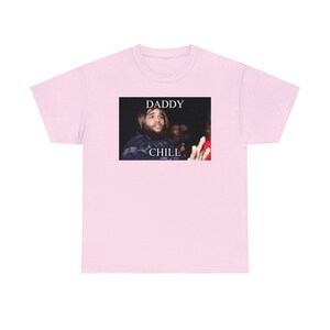 May include: Pink t-shirt with a black and white image of a man with long hair and a beard. The image has the text "Daddy Chill" on it.