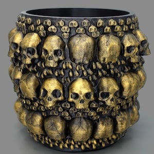 May include: Black planter pot with a gold skull design. The pot is decorated with multiple rows of skulls, each with a detailed face.