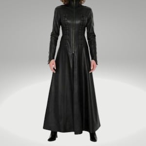 Puede incluir: Un largo abrigo de cuero negro con cuello alto y cierre de cremallera. El abrigo tiene un corpiño ajustado y una falda fluida.