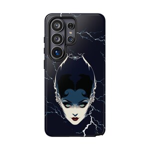 May include: A black smartphone case featuring a graphic illustration of a pale-skinned face with dark hair, sharp features, and green eyes. The background is a dark navy blue with white lightning bolt patterns extending across the entire surface.