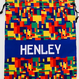 May include: A blue drawstring bag with a colourful Lego block pattern and the name "HENLEY" printed in white on a blue stripe.