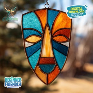 May include: A stained glass mask in a shield shape, featuring a face design with blue, orange, and white glass pieces. The mask has a dark brown metal frame and is suspended by a chain. Text on the image reads "DIGITAL DOWNLOAD NO PHYSICAL ITEM WILL BE SHIPPED" and "BEGINNER FRIENDLY".