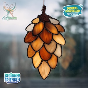 May include: Stained glass pinecone suncatcher with shades of brown, amber, and cream. The suncatcher is hanging in front of a window. The text "Digital Download" and "Beginner Friendly" are visible.