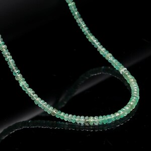 May include: A green emerald gemstone beaded necklace. The necklace is made of small, round beads that are strung together on a thin chain.
